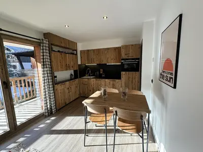 a kitchen with a wooden table and some chairs at Marmots Clan Megève in Megève