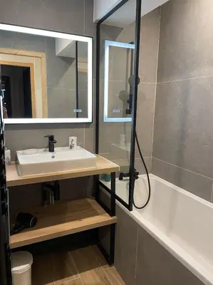 a bathroom with a sink and a mirror and a tub at Marmots Clan Megève in Megève
