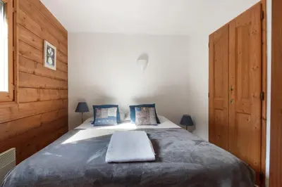 a bedroom with a large bed with blue pillows at Le Grand Tetras - Beside Lake Chavants, TMB staring point & Hikes in Les Houches