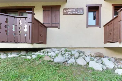 a building with brown doors and a pile of rocks at Le Grand Tetras - Beside Lake Chavants, TMB staring point & Hikes in Les Houches