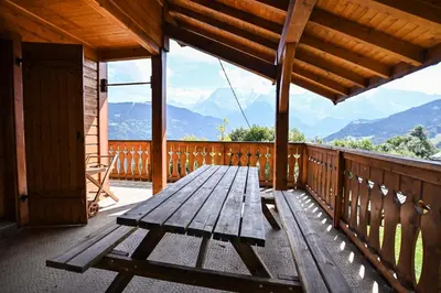 a wooden bench sitting on the deck of a cabin at Nice Peaceful Cottage With Garden And Balcony in Saint-Gervais-les-Bains