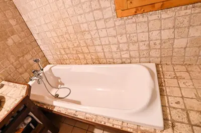 a bath tub in a bathroom with a tiled wall at Nice Peaceful Cottage With Garden And Balcony in Saint-Gervais-les-Bains