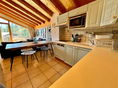 a kitchen with white cabinets and a table and chairs at Appartement chaleureux avec balcon près du centre - FR-1-624-112 in Samoëns