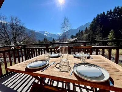 a wooden table with plates and glasses on a balcony at Appartement chaleureux avec balcon près du centre - FR-1-624-112 in Samoëns