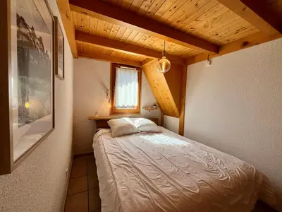 a bedroom with a bed in a room with wooden ceilings at Appartement chaleureux avec balcon près du centre - FR-1-624-112 in Samoëns