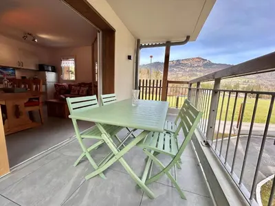 a green table and chairs on a balcony with a view at Appartement neuf avec balcon et navette pour le ski - FR-1-624-113 in Samoëns