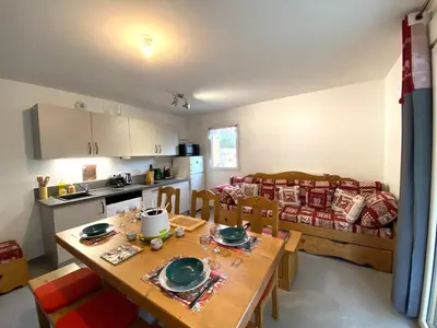 a kitchen and living room with a wooden table and chairs at Appartement neuf avec balcon et navette pour le ski - FR-1-624-113 in Samoëns