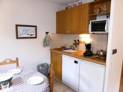 a small kitchen with a table and a white refrigerator at Résidence Palmes D'or - Palmes d'Or B109 MAE-5504 in Les Contamines-Montjoie