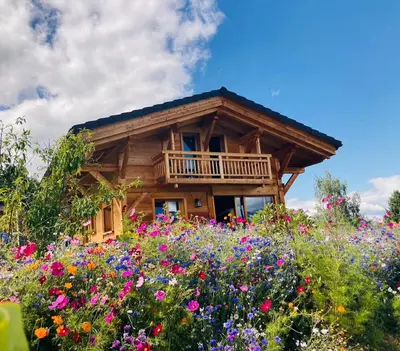 a log cabin with a field of flowers at Chalet récent vue panoramique sur le MONT-BLANC in Combloux