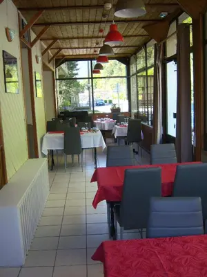 a restaurant with tables and chairs with red table cloth at Hotel Edelweiss in Magland