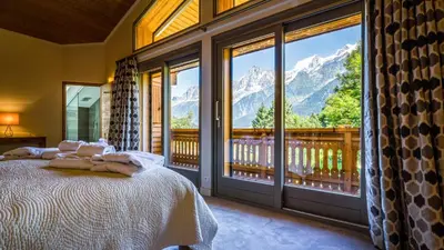 a bedroom with a bed and a balcony with mountains at Chalet Birdie in Les Houches