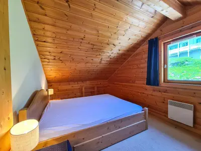 a bed in a wooden room with a window at Chalet lumineux · Sauna privatif · Garage · 12 personnes - FR-1-425-119 in Arâches-la-Frasse
