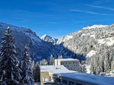 a snow covered mountain with a building and a tree at Appartement rénové 2 pièces pour 6, balcon proche pistes et commerces - FR-1-425-158 in Arâches-la-Frasse