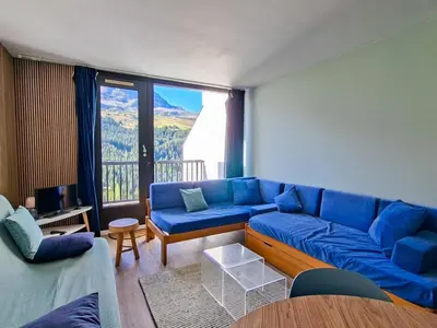 a living room with a blue couch and a large window at Appartement confortable au pied des pistes avec Wifi gratuit - FR-1-425-137 in Arâches-la-Frasse