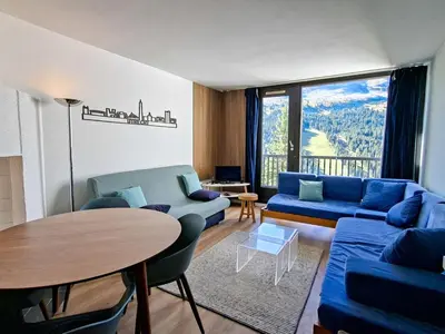 a living room with a blue couch and a table at Appartement confortable au pied des pistes avec Wifi gratuit - FR-1-425-137 in Arâches-la-Frasse