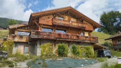 a large wooden house with a balcony and a pond at L'Eterlou 74 in Sallanches
