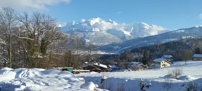 a snow covered village with mountains in the background at L'Eterlou 74 in Sallanches