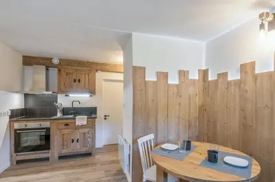 a kitchen and dining room with a wooden table at Studio Loup - L'Igloo - Welkeys in Combloux