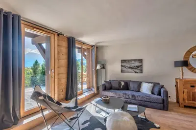 a living room with a couch and a large window at Appartement Vue Montagnarde - Welkeys in Combloux