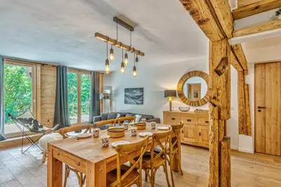 a dining room and living room with a wooden table and chairs at Appartement Vue Montagnarde - Welkeys in Combloux