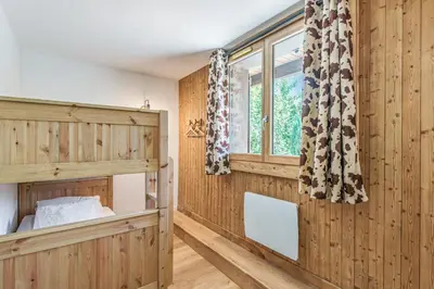 a bedroom with wooden walls and a bed and a window at Appartement Vue Montagnarde - Welkeys in Combloux