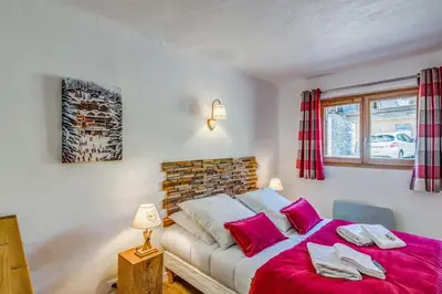 a bedroom with a large bed with pink pillows at Appartement Alpage - Welkeys in Combloux