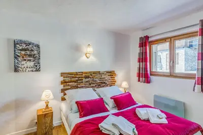 a bedroom with a large bed with red sheets at Appartement Alpage - Welkeys in Combloux
