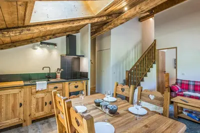 a kitchen and dining room with a wooden table and chairs at Appartement Alpage - Welkeys in Combloux