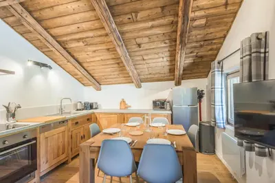 a kitchen with a wooden table and blue chairs at Appartement La Combe aux Loups - Welkeys in Combloux