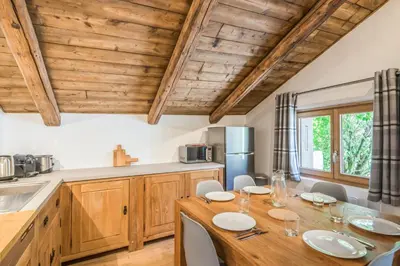a kitchen with a wooden table and chairs and a kitchen with wooden ceilings at Appartement La Combe aux Loups - Welkeys in Combloux