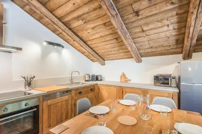 a kitchen with wooden cabinets and a wooden table with chairs at Appartement La Combe aux Loups - Welkeys in Combloux