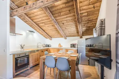 a kitchen with a wooden table and blue chairs at Appartement La Combe aux Loups - Welkeys in Combloux