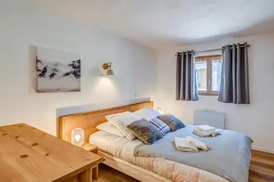 a bedroom with a bed and a wooden table at Appartement La Combe aux Loups - Welkeys in Combloux