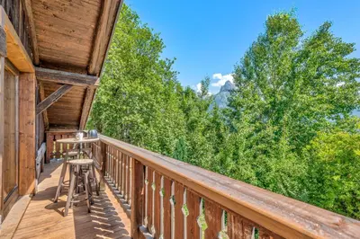a balcony of a cabin with a view of trees at Appartement La Pause de l'Ours - Welkeys in Combloux