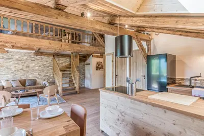a kitchen and living room with a table and a couch at Appartement La Pause de l'Ours - Welkeys in Combloux