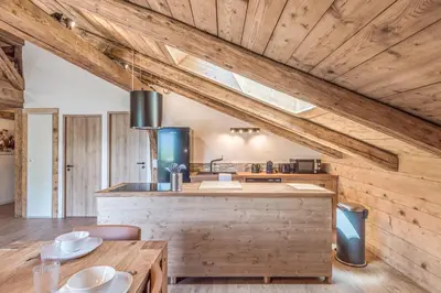 a kitchen with wooden ceilings and a wooden table at Appartement La Pause de l'Ours - Welkeys in Combloux