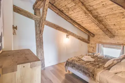 a bedroom with a large bed and a wooden ceiling at Appartement La Pause de l'Ours - Welkeys in Combloux
