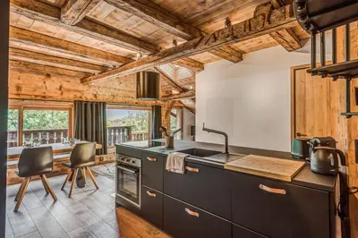 a kitchen with black cabinets and wooden ceilings at Appartement Le Mont-Blanc - Welkeys in Combloux