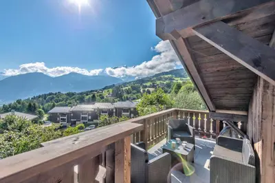 a deck with a table and chairs and mountains at Appartement Le Mont-Blanc - Welkeys in Combloux