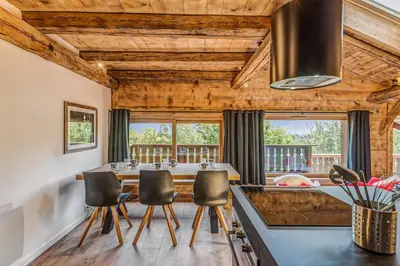 a dining room with a table and chairs and windows at Appartement Le Mont-Blanc - Welkeys in Combloux