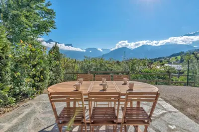 a wooden table and chairs with mountains in the background at Appartement Snow - Welkeys in Combloux