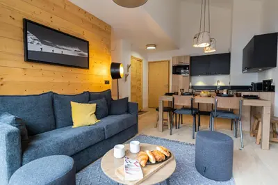 a living room with a blue couch and a kitchen at Les Roches du Mont Blanc - Résidence & Spa in Combloux