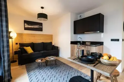a living room with a black couch and a table at Les Roches du Mont Blanc - Résidence & Spa in Combloux