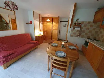 a living room with a table and a red couch at Les Pierres Blanches 2 pieces cosy et fonctionnel in Les Contamines-Montjoie