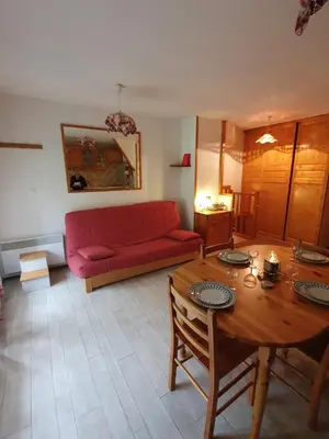 a living room with a red couch and a table at Les Pierres Blanches 2 pieces cosy et fonctionnel in Les Contamines-Montjoie