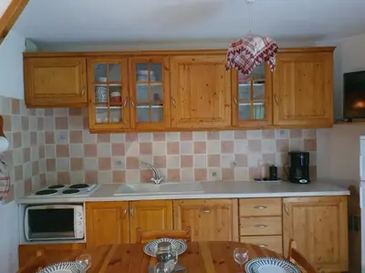 a kitchen with wooden cabinets and a table with chairs at Les Pierres Blanches 2 pieces cosy et fonctionnel in Les Contamines-Montjoie