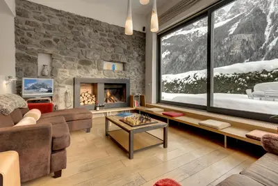 a house covered in snow with mountains in the background at Chalet Safari. Face au Mont-Blanc. in Chamonix-Mont-Blanc