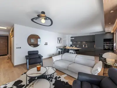 a living room with a couch and a kitchen at Appartement de Standing à Megève, 5 Min des Pistes, Sauna, Hammam, Parking, Animaux Acceptés - FR-1-569-52 in Megève