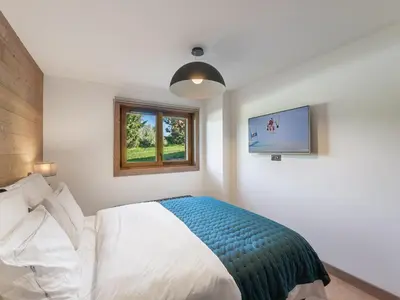 a bedroom with a bed and a window and a tv at Appartement de Standing à Megève, 5 Min des Pistes, Sauna, Hammam, Parking, Animaux Acceptés - FR-1-569-52 in Megève