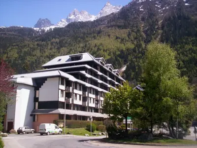 a large building with mountains in the background at Appartement Chamonix - 2 Pièces, Casier à ski, Près des bus - FR-1-517-62 in Chamonix-Mont-Blanc